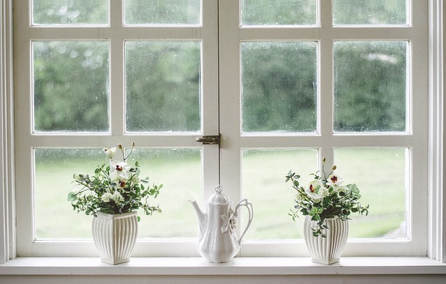 Porcelánový čajník a vázy na parapetnej doske pod dreveným oknom.jpg